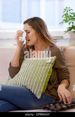 Suffering from a cold. a young woman being emotional and eating chocolates at home. Stock Photo