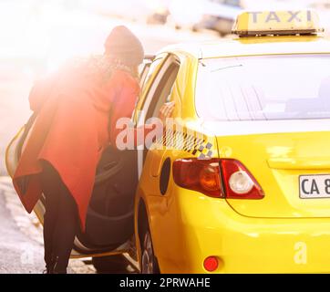 The only way to travel in the city. a fashionable young woman getting into a cab in the city. Stock Photo