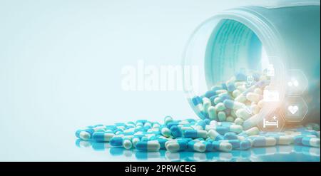 Blue and white capsules pills spilled out of white plastic bottle with medical and healthcare icon. Medical and healthcare concept. Hospital care and health insurance service. Hospital care budget. Stock Photo