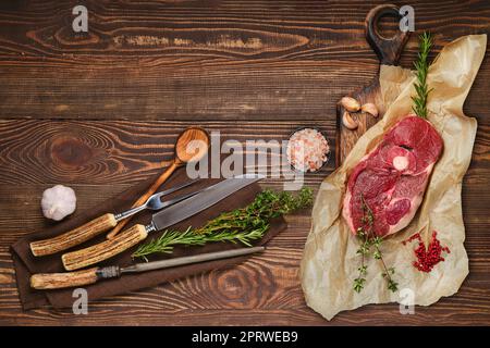 Raw fresh beef center cut leg steak with fork, knife and sharpener on napkin Stock Photo