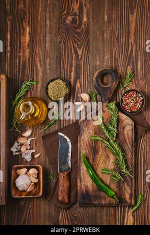 Top view of wooden cutting board with fresh rosemary and spices for piquant sauce or marinade Stock Photo
