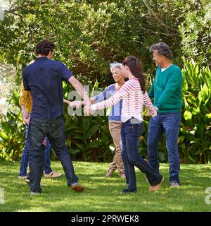 Round and round we go. Full length shot of a family playing together in the yard. Stock Photo
