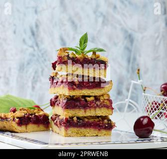 Square slices of cherry crumble lie in a stack on a white background. Stock Photo