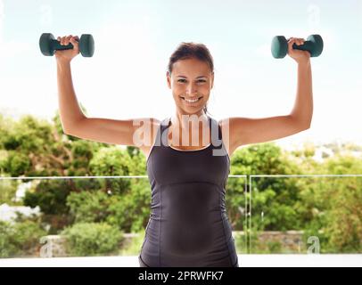 Better than the gym. Portrait of a sporty young woman working out with dumbbells. Stock Photo