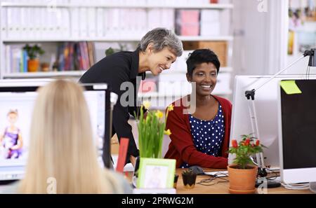 Getting the work done with a little help. two female designers discussing work on a desktop computer. Stock Photo