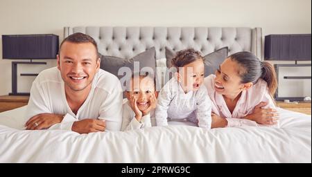 Portrait of family in home bedroom, young kids smile on bed and mother laughing with girl baby happiness. Face of happy father, morning cuddle together and funny mama relax in pyjamas on weekend rest Stock Photo