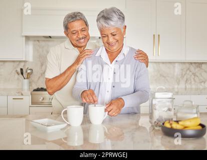Coffee, couple and love with a senior woman and man enjoying retirement while together in the kitchen of their home. Happy, smile and romance with an elderly male and female pensioner making tea Stock Photo