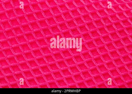 Red fabric texture. Close-up of an elastic scarlet nylon fabric with seamless pattern for sports equipment, backpacks, bags or other garments. Macro. Stock Photo