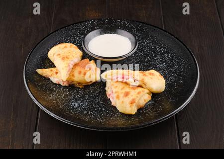 Thin pancakes stuffed with ham and cheese Stock Photo
