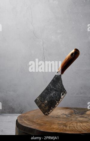 Old butcher's cleaver in wooden log Stock Photo