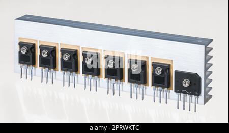 Electrical components on aluminum heat sink of switch-mode power supply on a white background. Insulated gate bipolar transistors and bridge rectifier Stock Photo