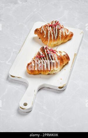Fresh croissant with raspberry jam on white board on marble background Stock Photo