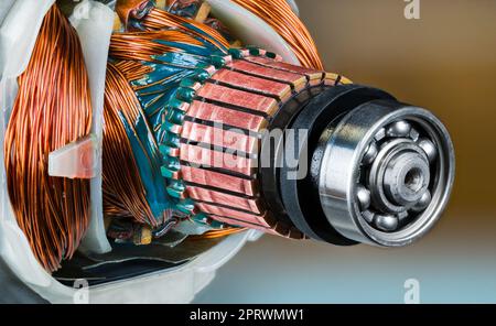 Closeup of ball bearing, commutator and rotor and stator inside electric DC motor. Copper wire with green epoxy in engine detail. Electronics industry. Stock Photo