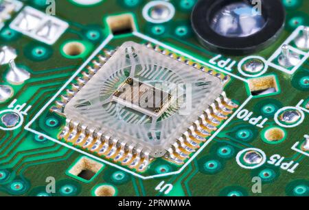 Closeup a microchip die inside optical sensor on green printed circuit board. Electronic square transparent surface mounted component to detect motion. Stock Photo
