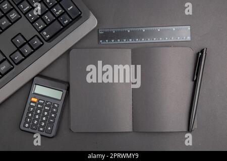 top view black notebook pen keyboard calculator lupa ruler on dark background Stock Photo