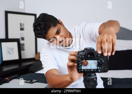 I know exactly what Im going to vlog about. a young man using a camera on a tripod to record himself at home. Stock Photo