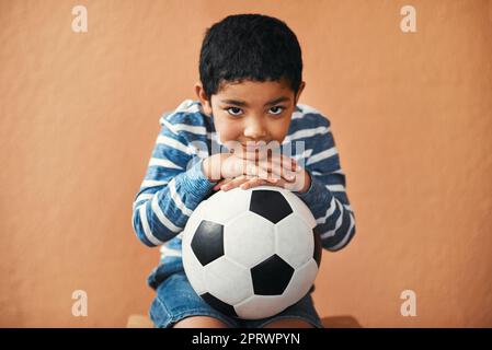 Will you play soccer with me. Portrait of an adorable little boy posing with a soccer ball. Stock Photo