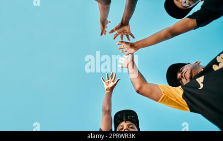 Attitude is everything. a team of young baseball players joining their hands together in a huddle during a game. Stock Photo