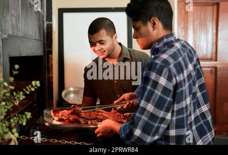 Chilling and grilling together. two young men grilling meat while having a barbecue. Stock Photo