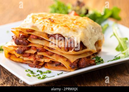 Portion of tasty lasagna on wooden table Stock Photo - Alamy