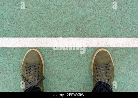Men feet in green leather sneakers stand on the rubberized track,  on a start line Stock Photo