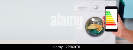 Person Operating Washing Machine Using Cellphone Stock Photo