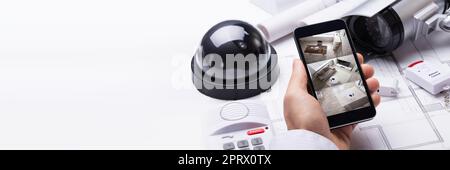 Person Hand Using Home Security System On Mobilephone Stock Photo