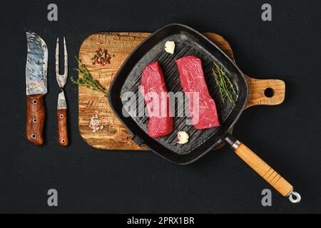 Overhead view of raw boneless beef loin steak on cast iron skillet Stock Photo