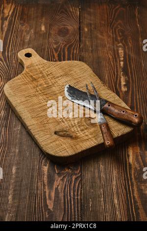 Rustic old cutting board with forged knife and fork Stock Photo