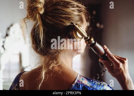 rear view portrait of woman with blonde hair talking on vintage phone in intimate interior room light Stock Photo