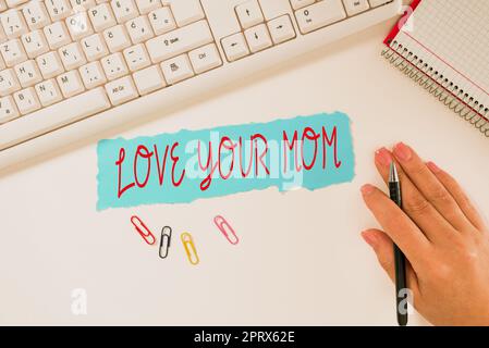 Handwriting text Love Your Mom, Word for Have good feelings about your mother Loving emotions Notebook With New Message On Desk With Pens, Headphones Stock Photo