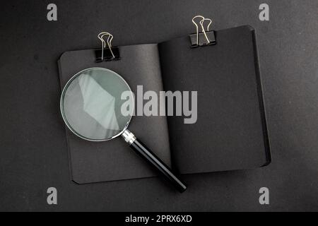 top view lack notepad binder clip lupa on black background Stock Photo
