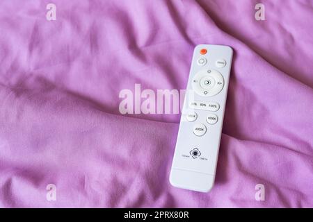 The remote control that controls the light on the ceiling, the chandelier is LED. Neon chandelier on the ceiling Stock Photo