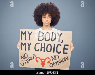 Black woman afro, protest and poster for abortion, female choice or decision against a studio background. Portrait of African American female taking a Stock Photo