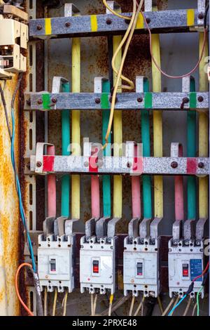 DUSHANBE, TAJIKISTAN - AUGUST 12, 2022: Many old rusty electrical fuse boxes with electic cables. Stock Photo