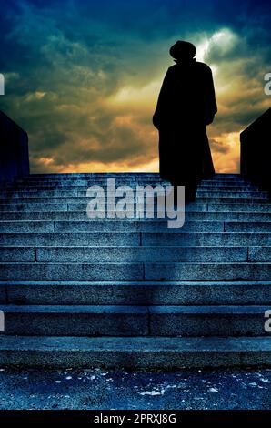 mysterious man wearing a hat standing on the top of a staircase Stock Photo