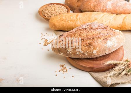 Different kinds of fresh baked bread on a white wooden background. side view, close up, copy space. Stock Photo