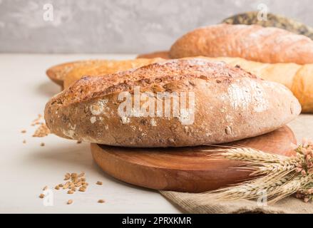 Different kinds of fresh baked bread on a white wooden background. side view, close up, selective focus. Stock Photo