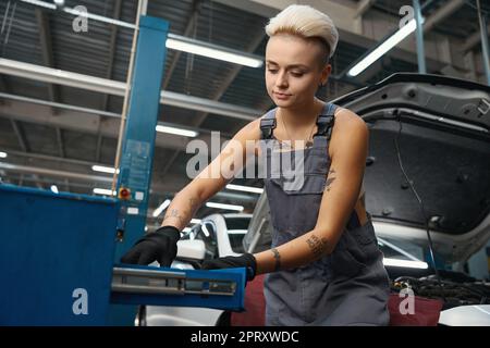 Woman auto repairman at workplace near working box with tools Stock Photo
