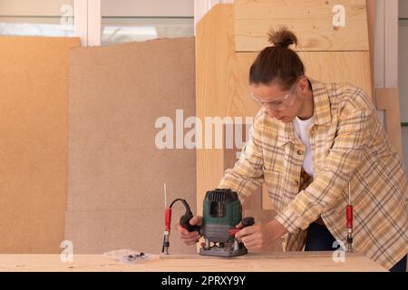 Young male carpenter using milling machine while working with wood in professional joinery workshop Stock Photo