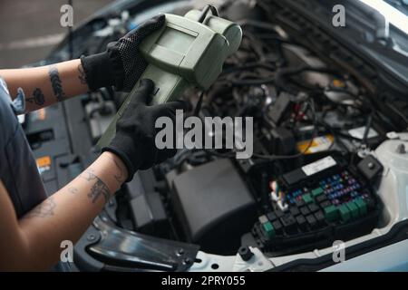 Car mechanic with a tattoo works under the hood Stock Photo