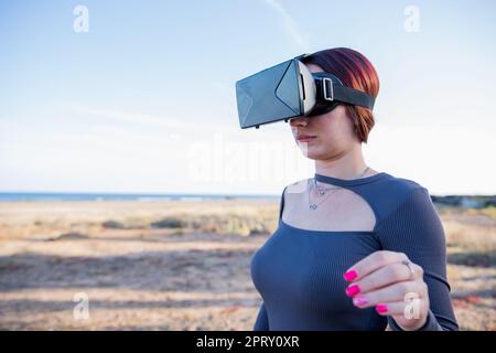 A tourist uses virtual reality headsets while at the beach, technology on vacation Stock Photo