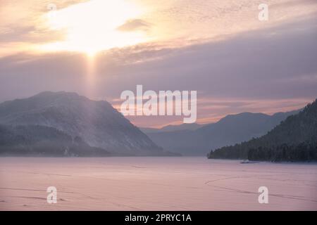 Beautiful sunset over the mountain lake Teletskoe in Altai in winter season. Stock Photo
