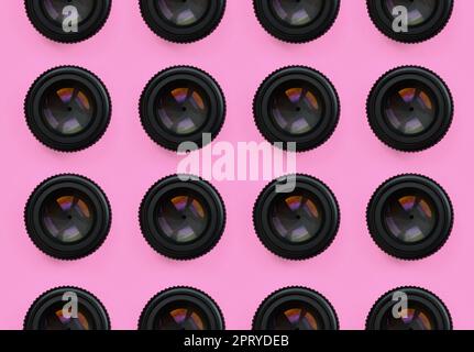 A few camera lenses with a closed aperture lie on texture background of fashion pastel pink color paper in minimal concept. Abstract trendy pattern. Stock Photo