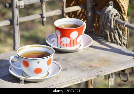 A rustic still-life with a cups of tea and a straw hat on a wooden hand-made shelf made from old dried bamboo. Cups of hot tea in the courtyard of the Stock Photo