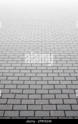 Photo of the site from the old paving slab with small defects and cracks, leaving in perspective. Street coverage of pedestrian areas and paths in par Stock Photo