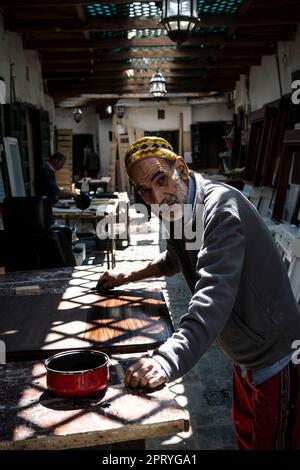 Carpenter varnishing a piece of wood at his work station in the Tetouan medina. Stock Photo