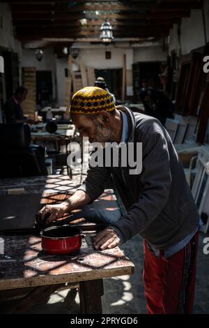 Carpenter varnishing a piece of wood at his work station in the Tetouan medina. Stock Photo