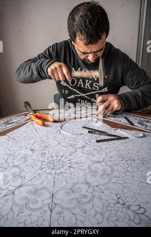 Craftsman carving ornaments on a wooden table with hammer and chisel. Stock Photo