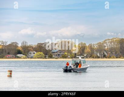 Three men on the back of a fishing boat One man seated with a